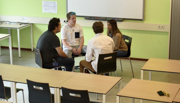 Welzijn collge vier studenten in kring in klaslokaa